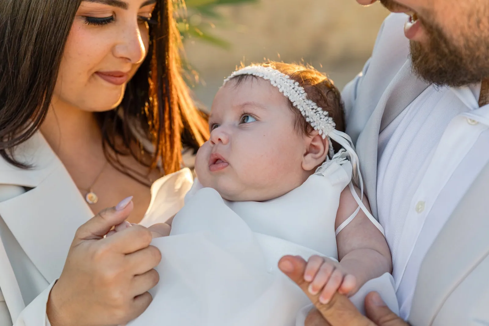 baby in white dress with parents malta