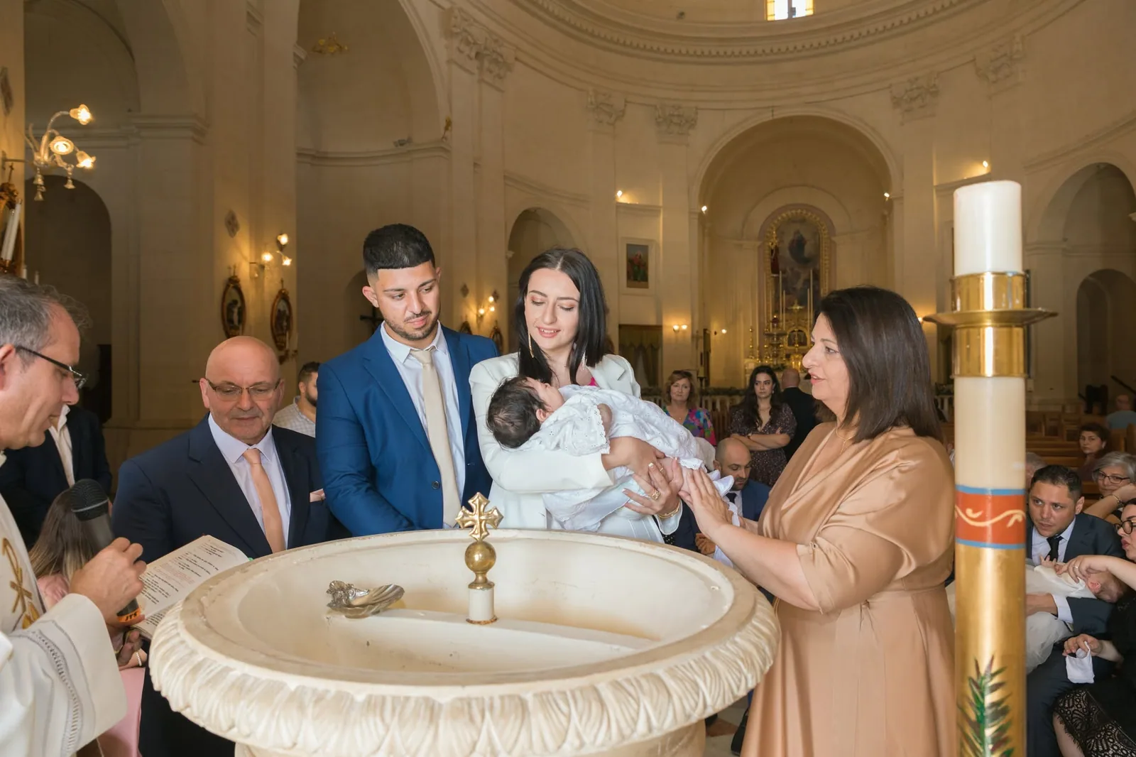 family gathered around church baptism font malta