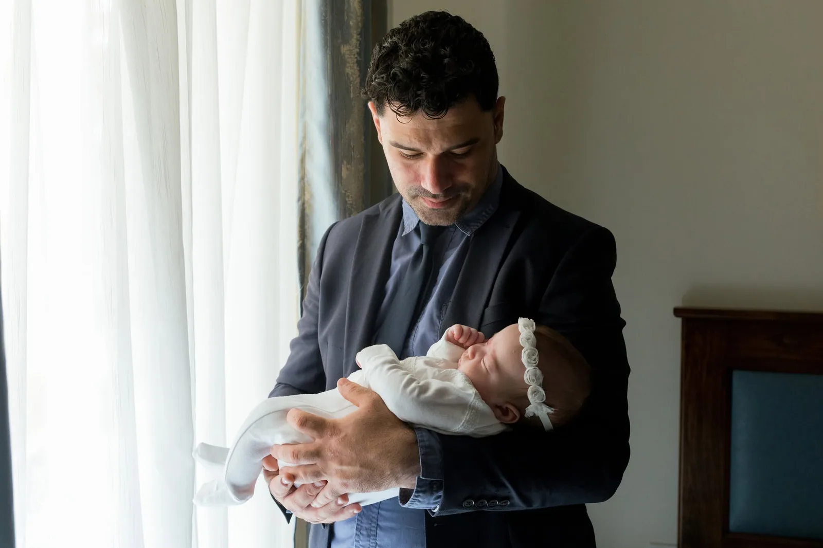 father cradling baby by window malta