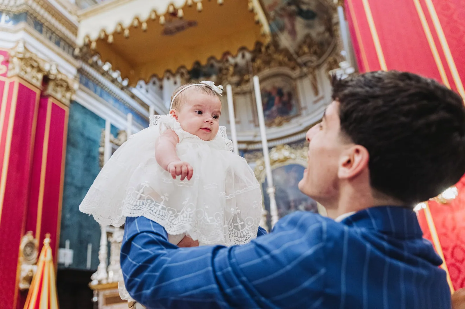 father lifting baby in church malta