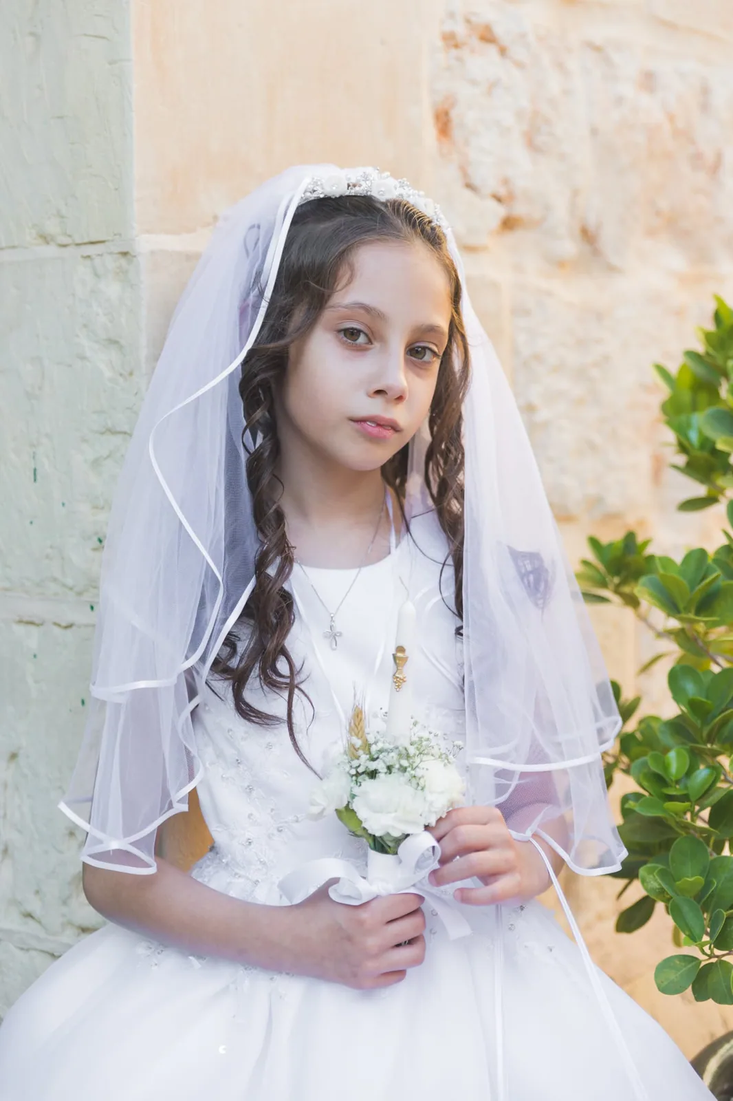 first communion girl with veil by stone wall malta