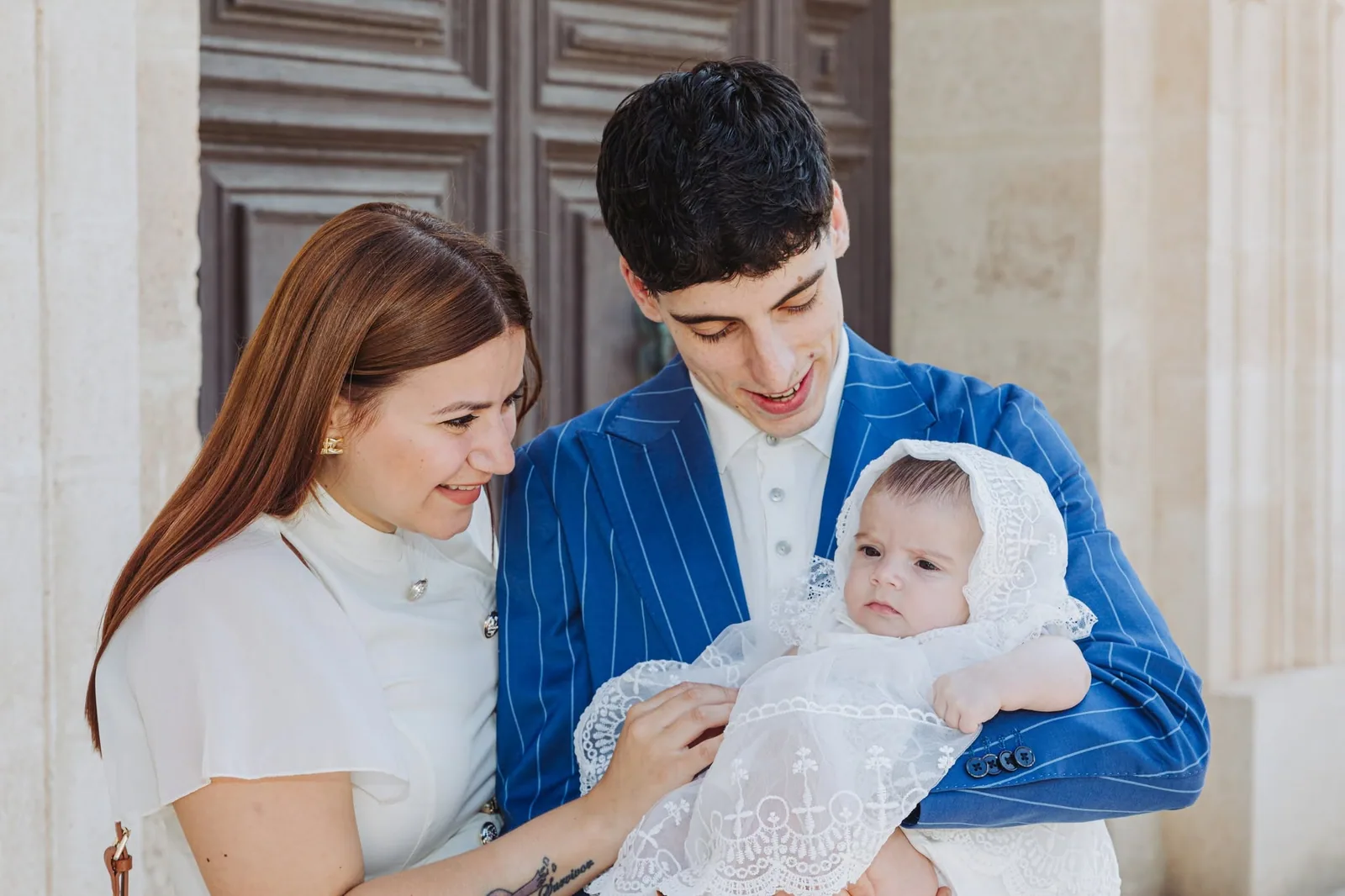 parents holding baby in christening gown malta