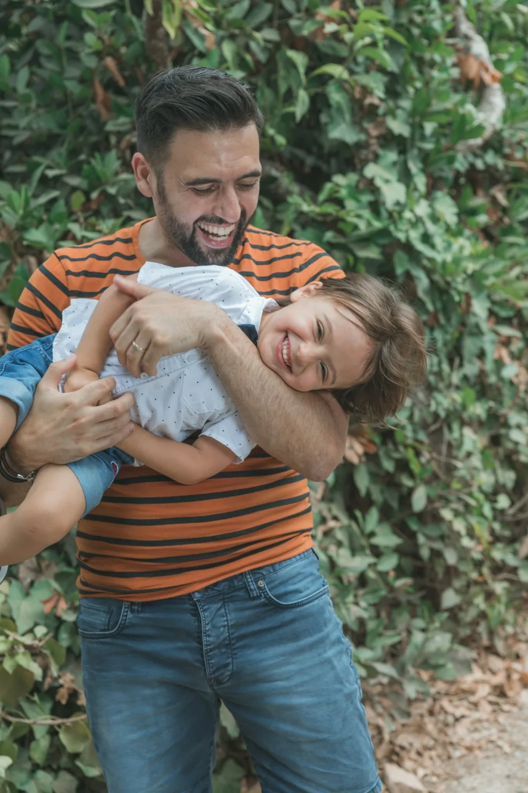 father cradling playful son in garden malta