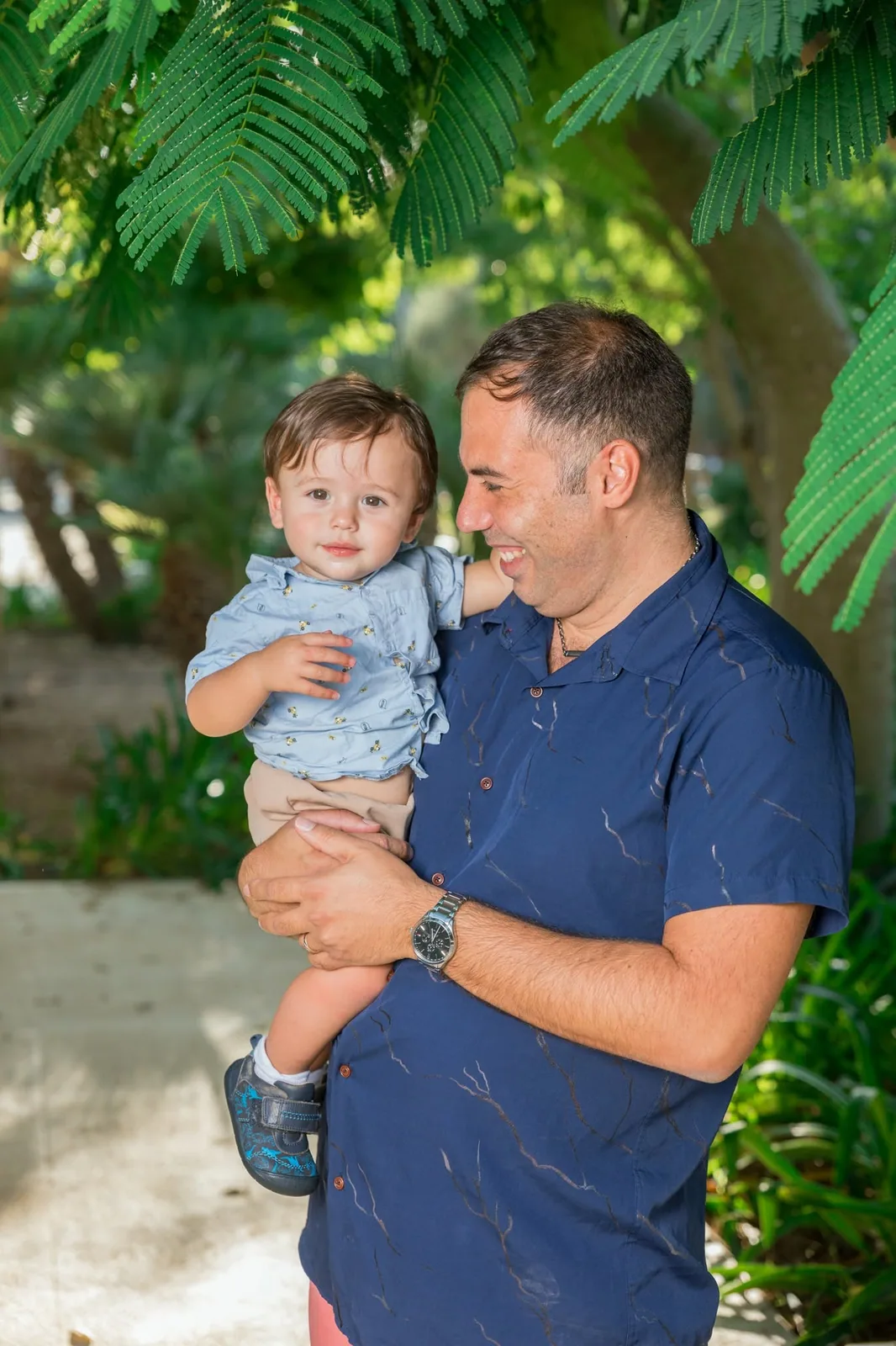 father holding toddler beneath leaves malta