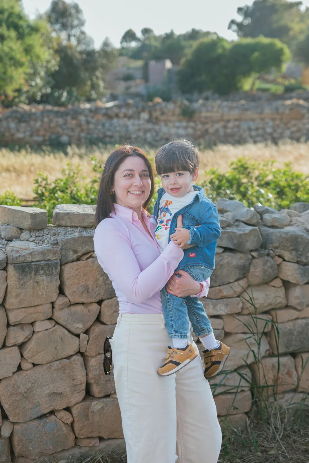 mother holding toddler by stone wall malta