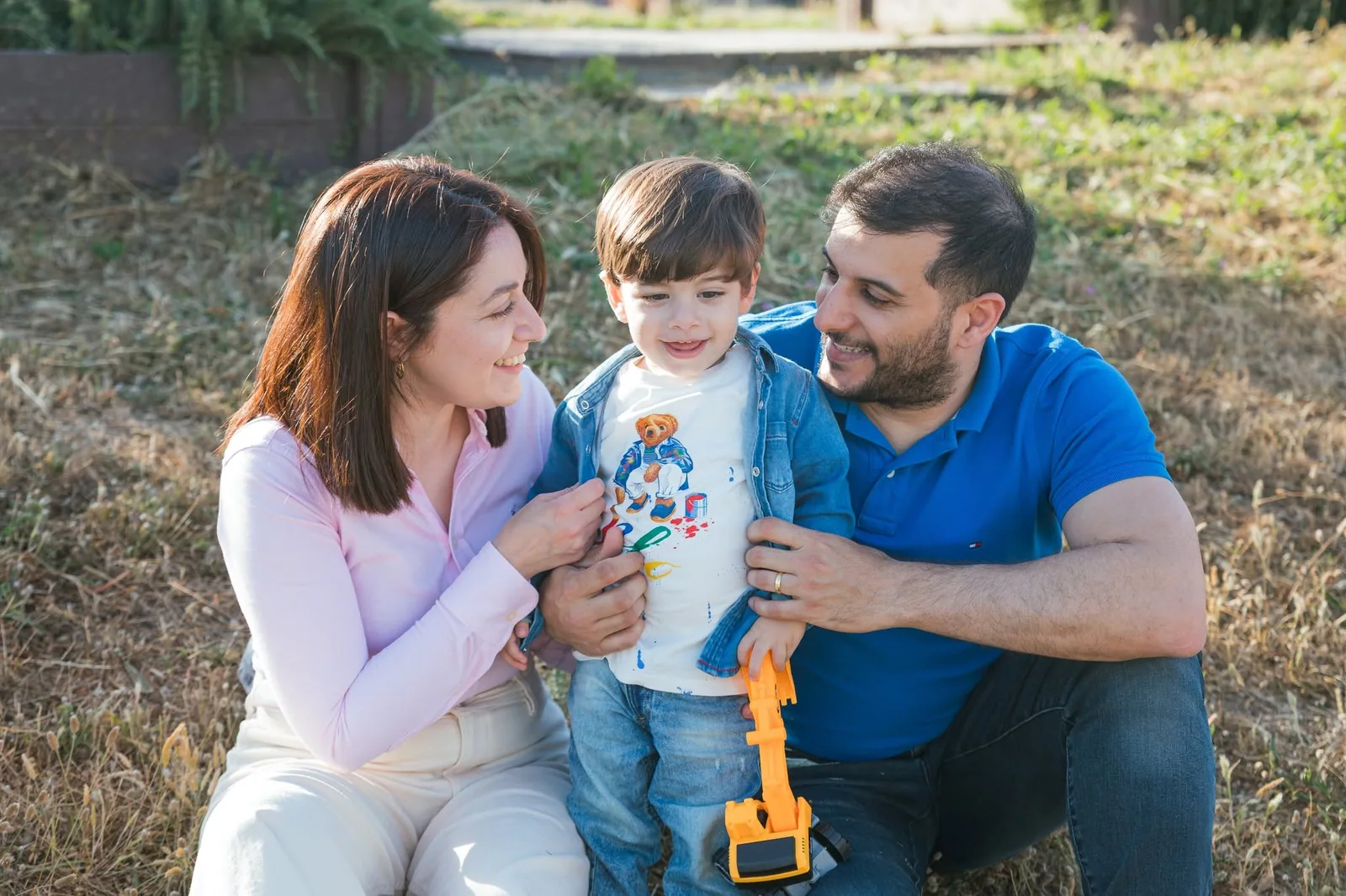 parents cuddling toddler in countryside malta