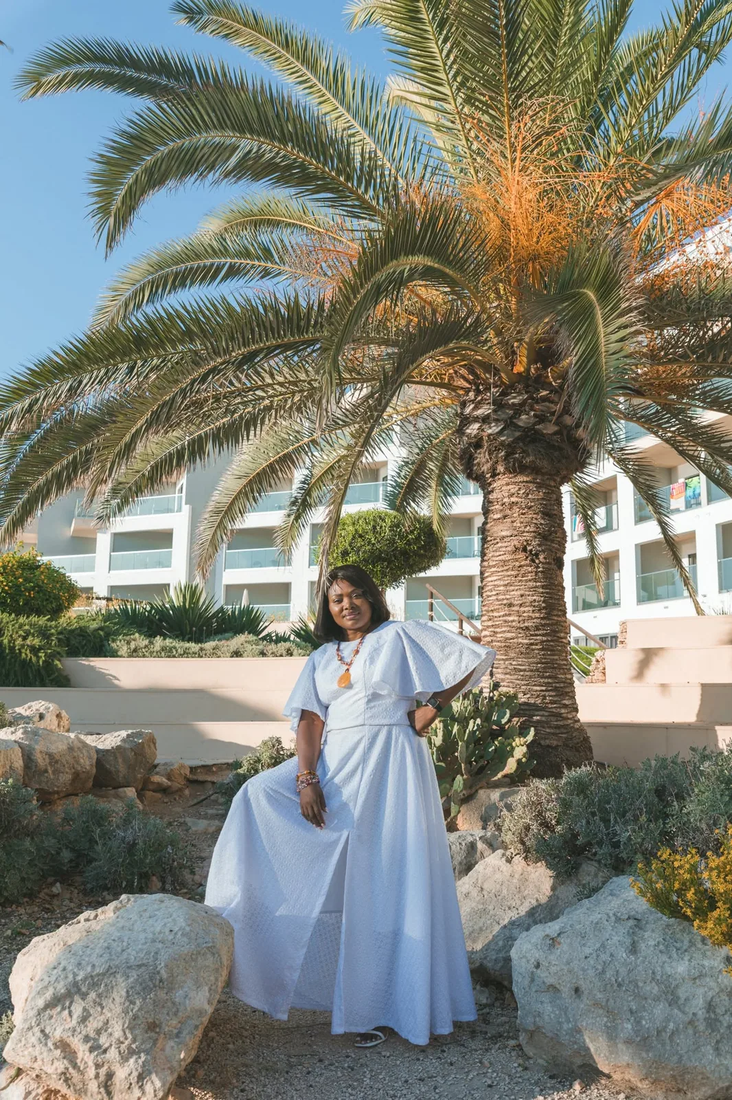 woman in white dress beneath palm tree malta