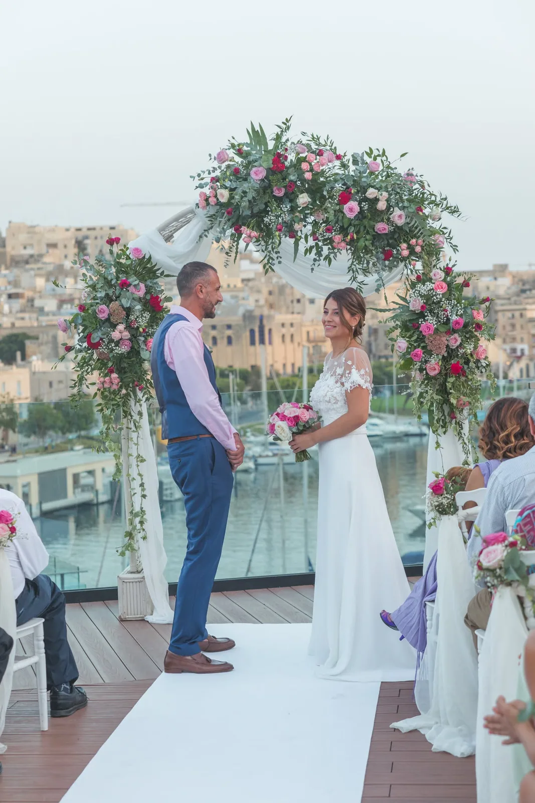 bride and groom exchanging vows under floral arch malta