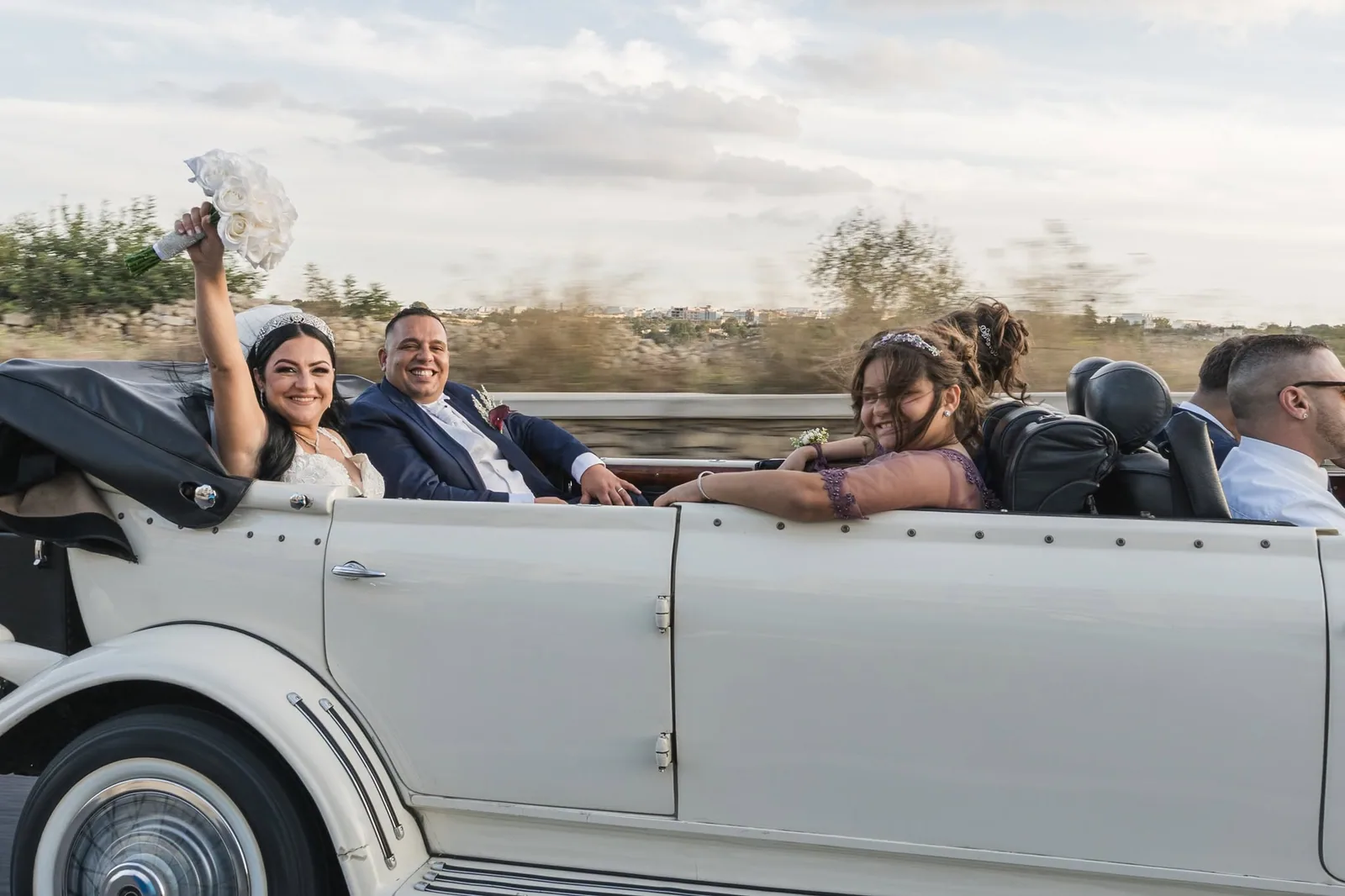 newlyweds waving from vintage convertible malta